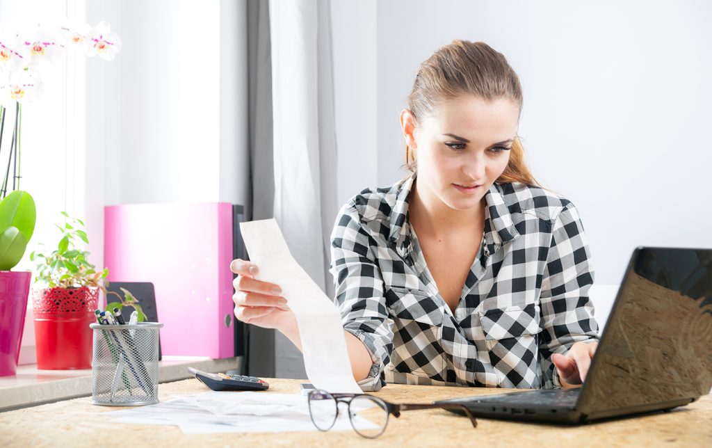smiling woman calculating and paying bills in home office