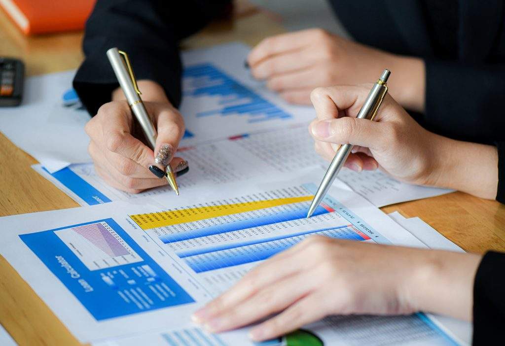 Dois analistas conferindo tabela com dados financeiros